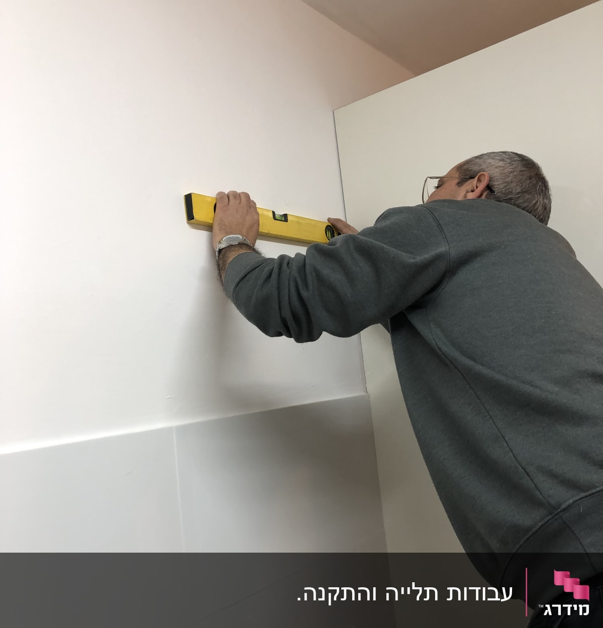 אדם משתמש בפלס על קיר לבן